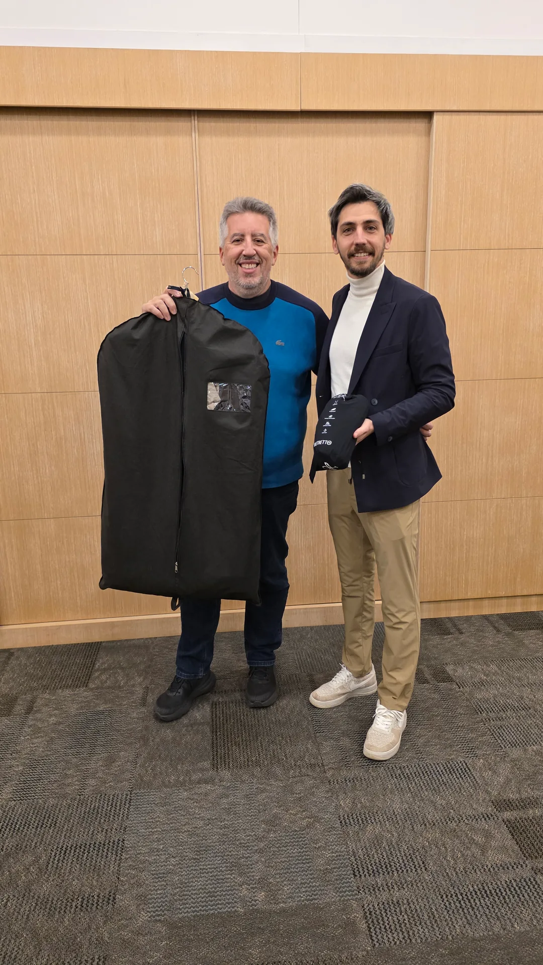 Dos hombres, uno con un portatrajes en la mano