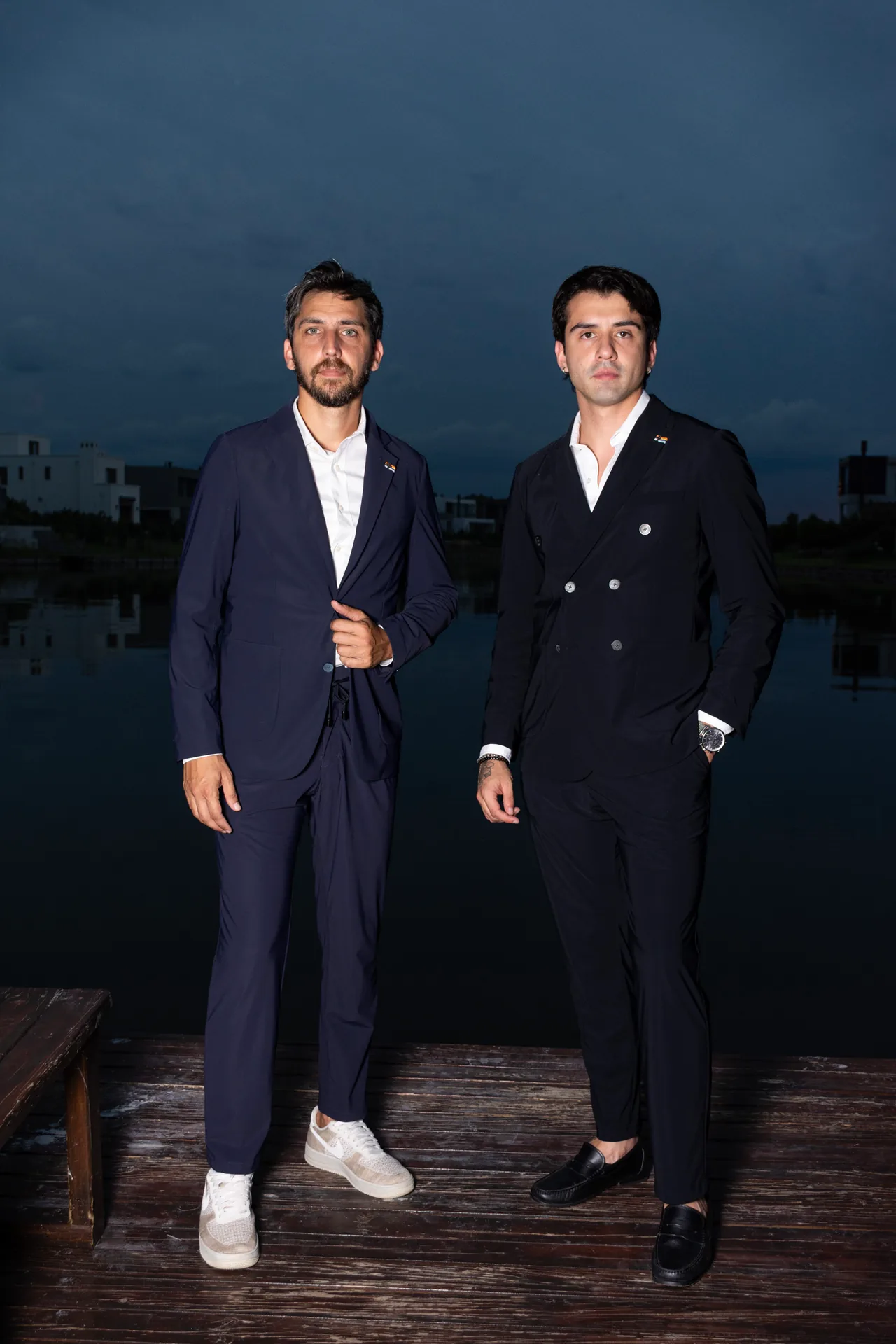 Lucho y Nacho, fundadores de Crux Sartorial, de traje en un muelle al atardecer.